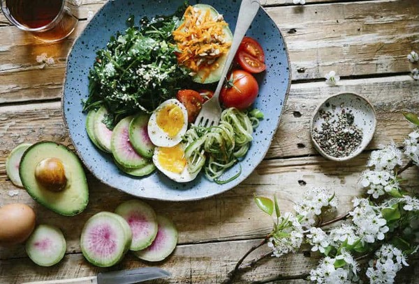 A colorful bowl filled with vegetables, grains, and seeds